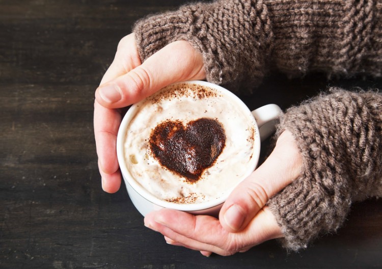 Hands Holding Warm Cappuccino with Froth and Cocoa Heart Shape